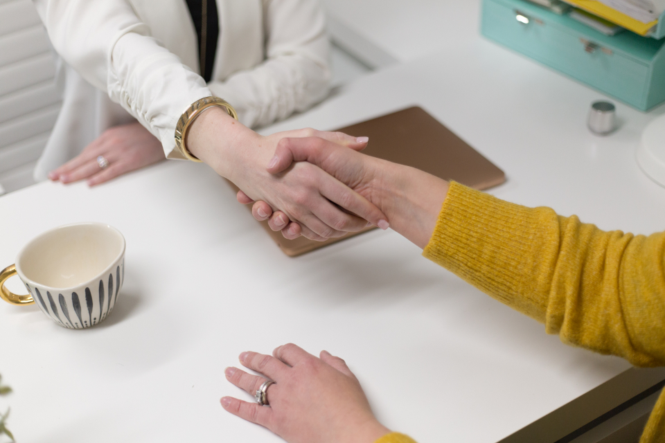 Apretón de manos entre dos personas en una mesa de trabajo