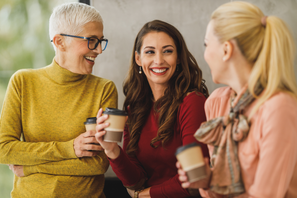Tres personas sonrientes conversando con un café, un entorno positivo y cercano